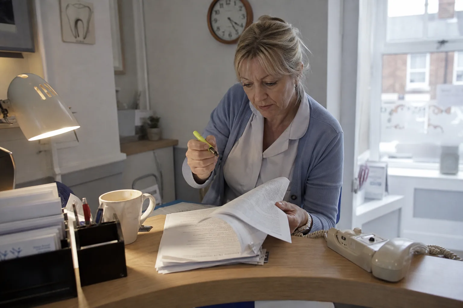 Dental clinic owner in England reading the small print of a long contract at the front desk, checking hidden fees