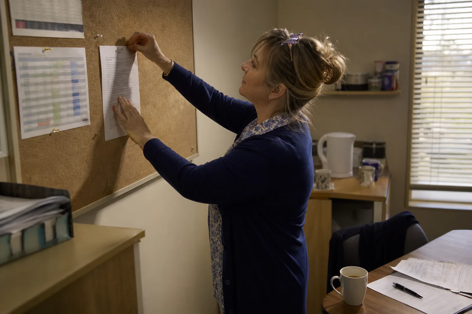 Clinic manager pinning a one-page call routing and escalation policy to the staff noticeboard after closing time
